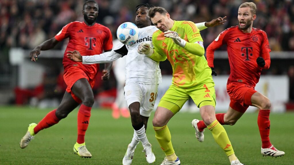 Manuel Neuer kommt zu spät und rammt Leverkusens Jeremie Frimpong um. Foto: Sven Hoppe/dpa