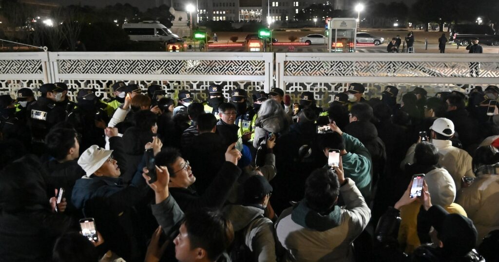 Des gens se rassemblent devant l'Assemblée nationale à Séoul, en Corée du Sud, le 4 décembre 2024, après que le président Yoon Suk Yeol a déclaré la loi martiale