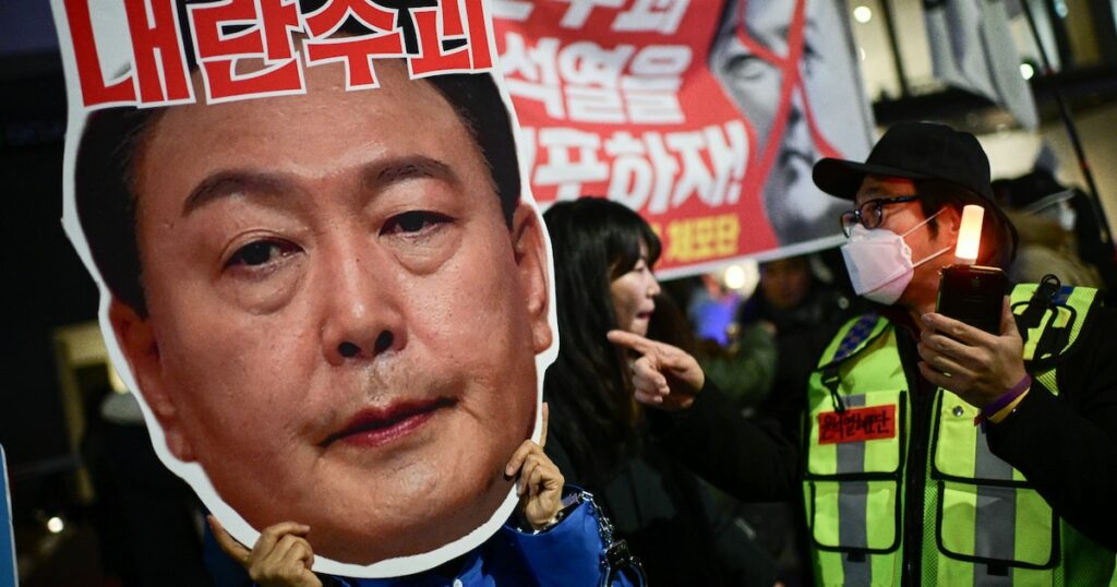 Un manifestant brandit un portrait du président sud-coréen Yoon Suk Yeol, lors d'un rassemblement pour sa démission, le 8 décembre 2024 à Séoul