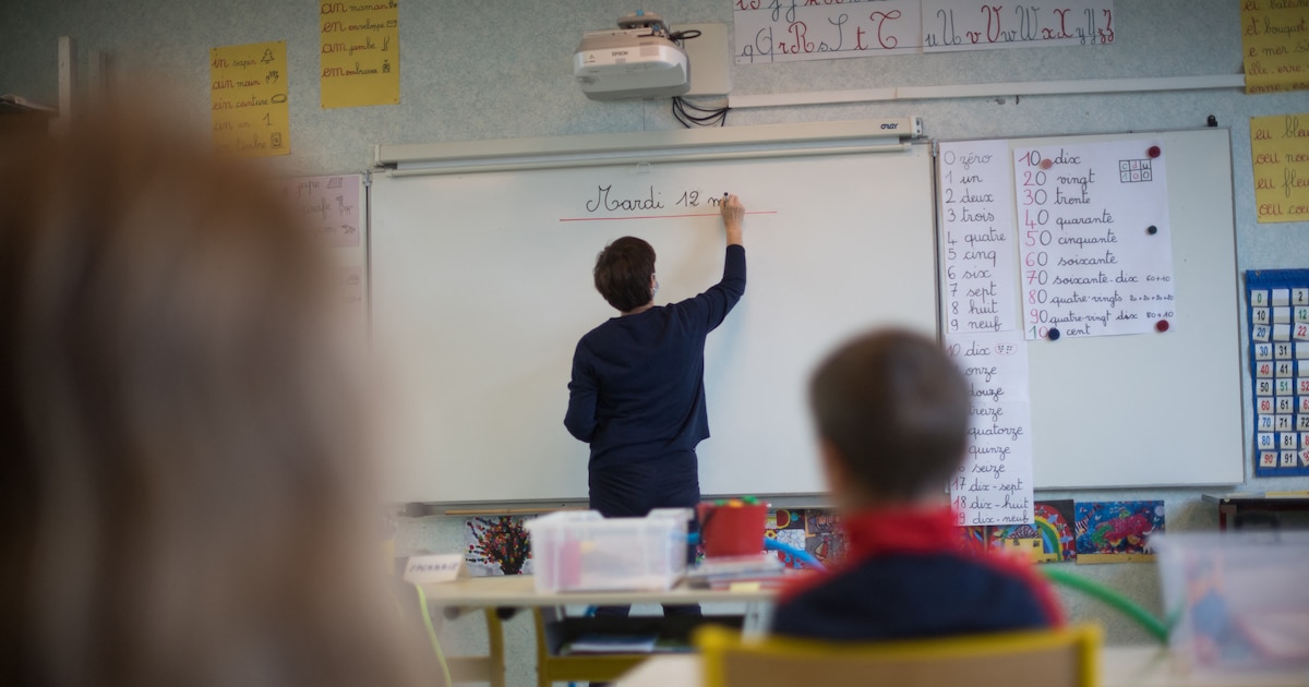 A teacher wearing a protective face mask works with pupils after they have returned to their classroom at the Trinite public school in the Groix island, on May 12, 2020, two days after France eased lockdown measures to curb the spread of the COVID-19 pandemic, caused by the novel coronavirus. (Photo by Loic VENANCE / AFP)