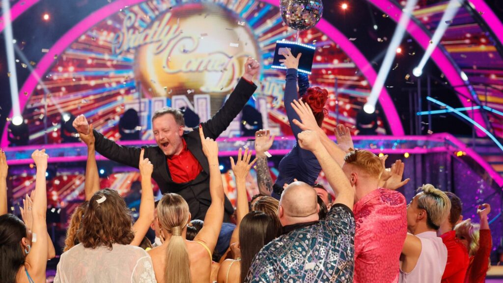 Chris McCausland celebrates his win, as Dianne Buswell holds the glitterball trophy aloft. Pic: PA