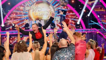 Chris McCausland celebrates his win, as Dianne Buswell holds the glitterball trophy aloft. Pic: PA