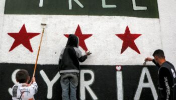 Le drapeau à trois étoiles de l'indépendance syrienne, adopté par le nouveau pouvoir, peint sur une maison de Homs avec les mots "La Syrie libre", le 16 décembre 2024