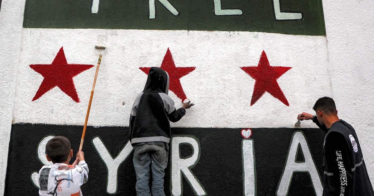 Le drapeau à trois étoiles de l'indépendance syrienne, adopté par le nouveau pouvoir, peint sur une maison de Homs avec les mots "La Syrie libre", le 16 décembre 2024