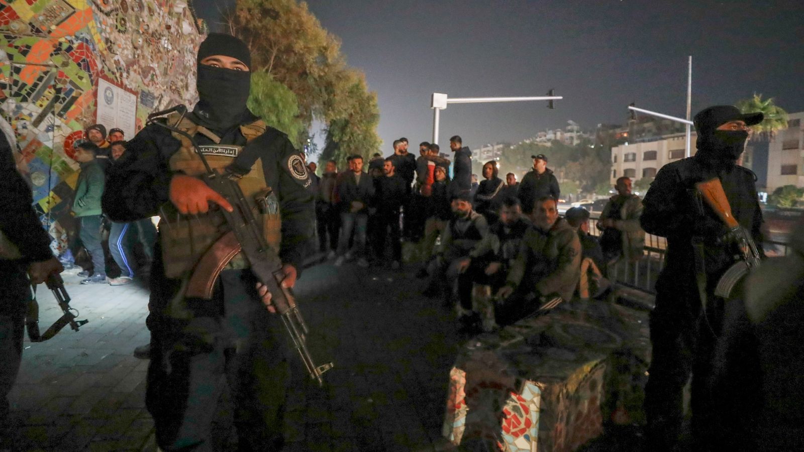 Security forces of the new Syrian government secure the area around group of Alawite protesters in the Mazzeh district in Damascus. Pic: AP