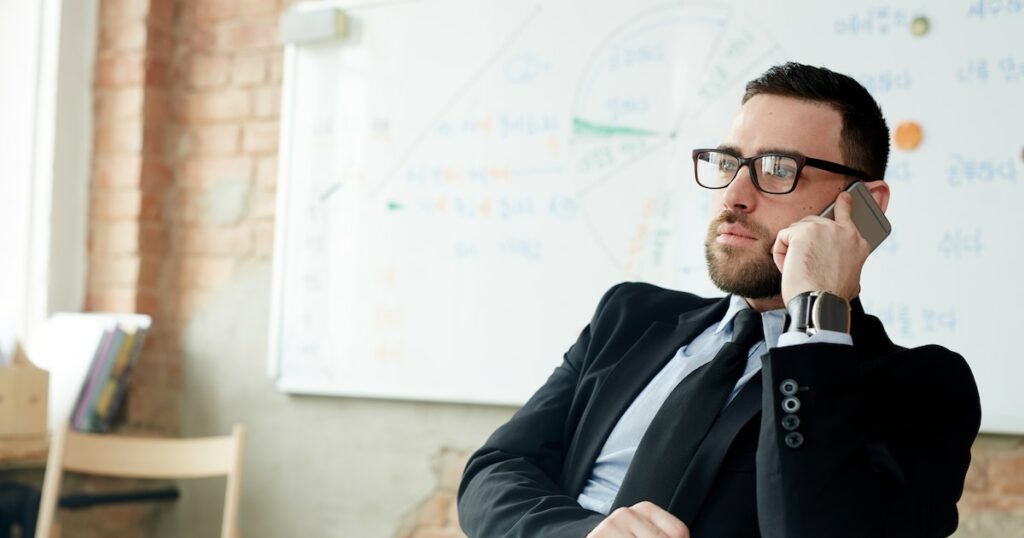 Confident employer calling by mobile phone in office