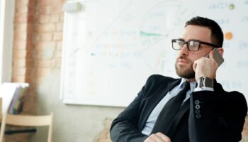 Confident employer calling by mobile phone in office