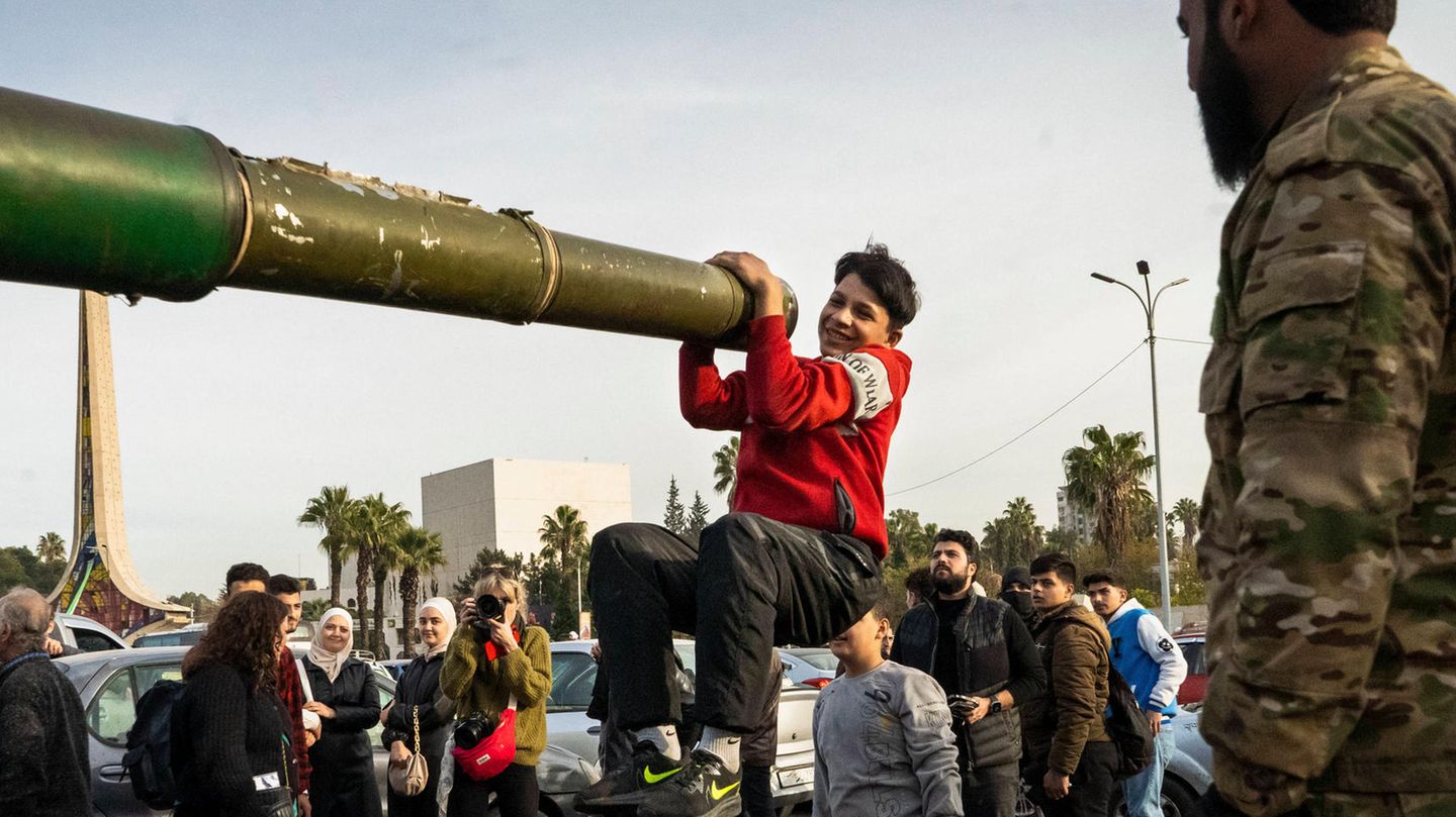 Ein Jugendlicher hält sich in Damaskus aus lauter Freude über den Umsturz in Syrien an einem Panzerrohr fest