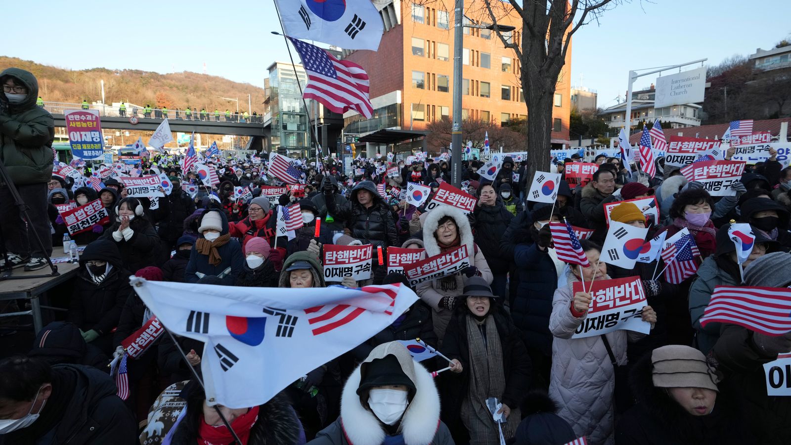 Supporters of impeached South Korean President Yoon Suk Yeol stage a rally to oppose a court having issued a warrant to detain Yoon, as police offices stand guard near the presidential residence in Seoul, South Korea, Friday, Jan. 3, 2025. The letters read "Oppose Impeachment." (AP Photo/Lee Jin-man)