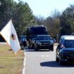 Members of the National Park Service watch as the hearse containing Jimmy Carter's coffin passes through his boyhood Farm in Archery, Georgia. Pic: Reuters