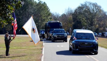 Members of the National Park Service watch as the hearse containing Jimmy Carter's coffin passes through his boyhood Farm in Archery, Georgia. Pic: Reuters