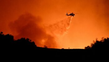 Un hélicoptère fait un largage sur des incendies en cours entre les quartiers de Mulholland drive et d'Encino, le 10 janvier 2025 à Los Angeles