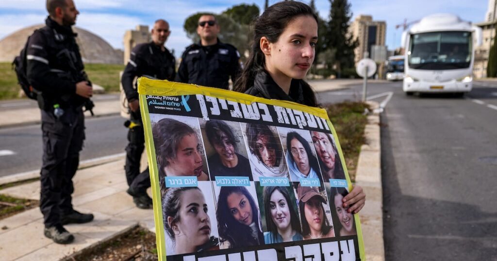 Une manifestante tient une pancarte avec des photos d'otages à Gaza lors d'un rassemblement appelant à une trêve dans la guerre contre le Hamas et à la libération des otages, devant le bureau du Premier ministre israélien à Jérusalem, le 14 janvier 2024