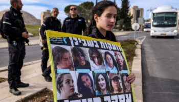 Une manifestante tient une pancarte avec des photos d'otages à Gaza lors d'un rassemblement appelant à une trêve dans la guerre contre le Hamas et à la libération des otages, devant le bureau du Premier ministre israélien à Jérusalem, le 14 janvier 2024