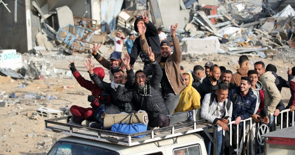 Des déplacés palestiniens font le V de la victoire à leur retour à bord d'une camionnette dans la ville de Rafah dans le sud de la bande de Gaza, le 19 janvier 2025