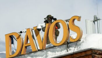 A police officer uses binoculars on a roof, ahead of the annual meeting of the World Economic Forum (WEF) in Davos, Switzerland