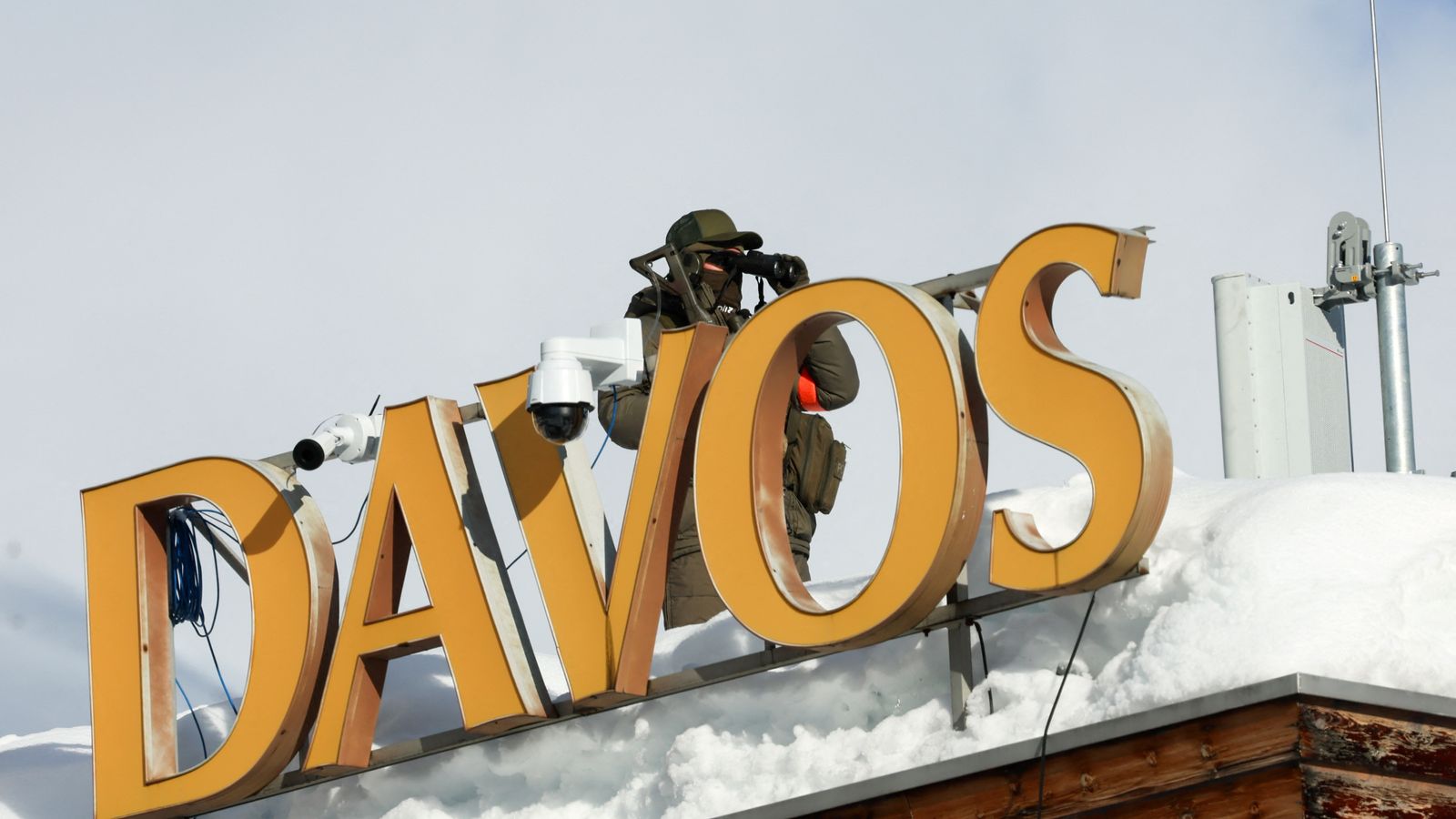 A police officer uses binoculars on a roof, ahead of the annual meeting of the World Economic Forum (WEF) in Davos, Switzerland