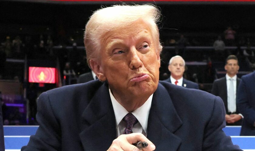 Donald Trump reacts as he signs an executive order during the inaugural parade inside Capital One Arena on the inauguration day of his second presidential term, in Washington, U.S. January 20, 2025. REUTERS/Carlos Barria