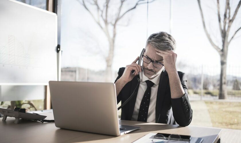 Worried businessman on the phone looking at laptop computer