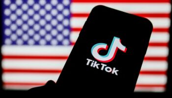 TikTok logo is seen displayed on a phone screen with American flag in the background in this illustration photo taken on August 2, 2020. President of the USA Donald Trump said that Chinese app TikTok will be banned in the United States. (Photo Illustration by Jakub Porzycki/NurPhoto) (Photo by Jakub Porzycki / NurPhoto / NurPhoto via AFP)