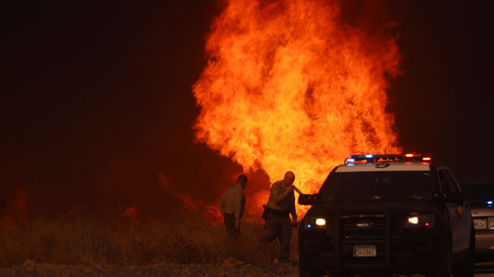 Officers take cover from the Hughes Fire in Los Angeles, California. Pic: Reuters