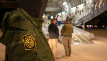 This photo provided by the U.S. Dept. of Defense, A U.S. Customs and Border Protection agent watches as undocumented immigrants are loaded onto a C-17 Globemaster III at Tucson International Airport in Tucson, Ariz., Thursday, Jan. 23, 2025.  (Senior Airman Devlin Bishop/Dept. of Defense via AP)