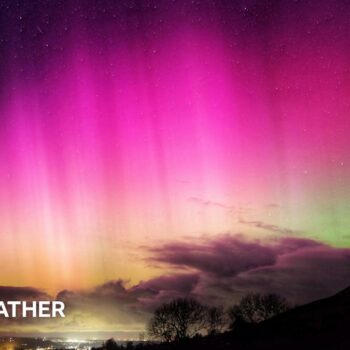 bright pinks in the night sky of the aurora.  Some cloud on the horizon with a green tinge behind the cloud.