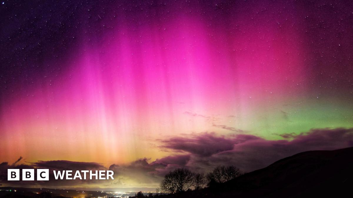 bright pinks in the night sky of the aurora.  Some cloud on the horizon with a green tinge behind the cloud.