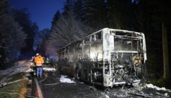 Einsatzkräfte stehen neben einem ausgebrannten Bus. Der Linienbus ist im Kreis Biberach in Brand geraten. Foto: Ralf Zwiebler/dp