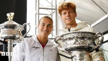 Aryna Sabalenka and Jannik Sinner pose with the Australian Open trophies at Melbourne Park