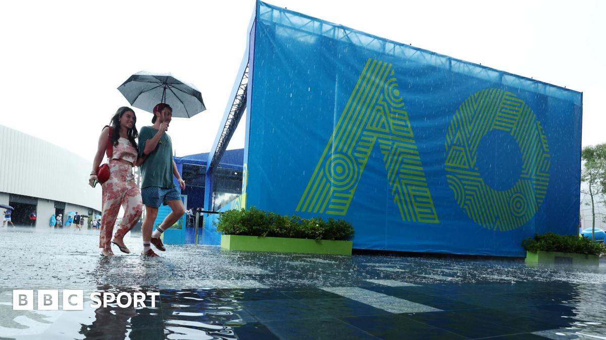 Fans arrive at Melbourne Park under an umbrella