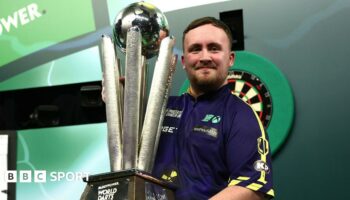 Luke Littler lifts the PDC World Darts Championship trophy at Alexandra Palace