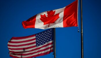 The flags of Canada and the United States fly outside a hotel in downtown Ottawa, on Saturday, Feb. 1, 2025. (Justin Tang/The Canadian Press via AP)