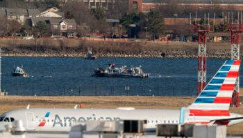 Police and coast guard boats are seen around a wreckage site in the Potomac River as an American Airlines plane passes in the foreground at Ronald Reagan Washington National Airport, Saturday, Feb. 1, 2025, in Arlington, Va., (AP Photo/Jose Luis Magana)