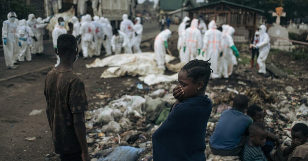 De jeunes habitants regardent des membres de la Croix-Rouge congolaise et de la Protection civile enterrer des dizaines de corps, le 3 février 2025 dans un cimetière de Goma en RDC