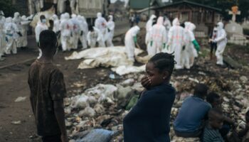 De jeunes habitants regardent des membres de la Croix-Rouge congolaise et de la Protection civile enterrer des dizaines de corps, le 3 février 2025 dans un cimetière de Goma en RDC