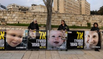 Des proches d'otages israéliens à Gaza tiennent des photos d'une mère et de ses deux enfants encore captifs, lors d'une manifestation devant le bureau du Premier ministre à Jérusalem, le 3 février 2025