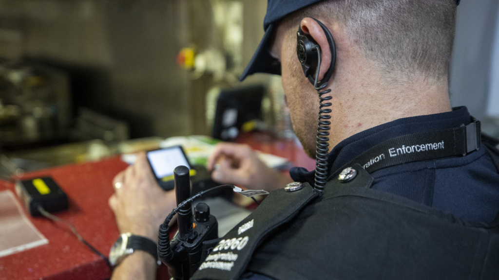 Immigration enforcement officer using a portable photo printer during an immigration raid in Warrenpointin County Down, Northern Ireland. Picture date: Thursday August 10 2023.