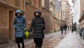 Rain falls as people make their way along Senate House Passage in Cambridge. Pic: Joe Giddens/PA Wire